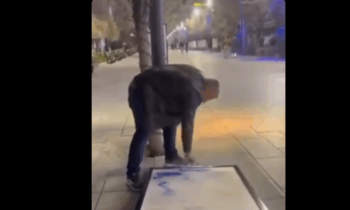 Një qytetar e rrëzon dhe e ngjyros një nga tabelat e ekspozitës me gabime në sheshin e Prishtinës